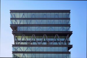 Modern glazen kantoorgebouw aan de Joan Muyskenweg met opvallende stalen X-structuren in de gevel.